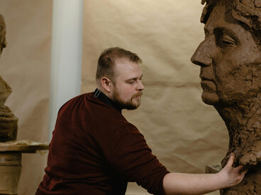 A sculptor shaping clay in a cluttered studio, where the chaos of creation becomes a personal sanctuary