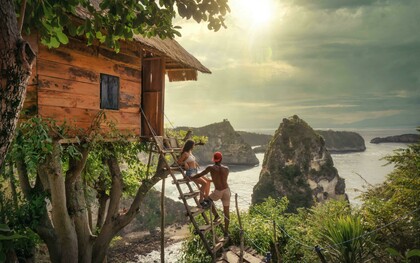 A couple sits on a brown wooden ladder in Bali, Indonesia, enjoying a quiet moment