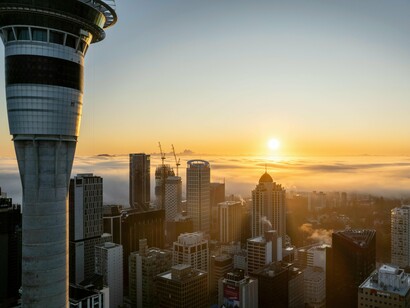 A misty Auckland skyline, symbolizing the uncertainty small economies face when export gains don’t translate into household resilience