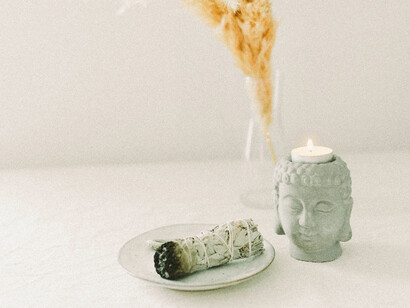 A sage bundle and Buddha head candle conveys a cleansing body and space ritual