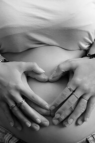 In eager anticipation, a loving man tenderly cuddles his pregnant wife, both excitedly awaiting the arrival of their baby, embracing the precious moments together