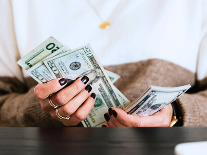 A person quietly calculating cash, symbolizing the subtle anxieties of financial dependence