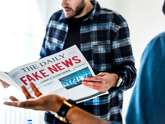 Men reading a newspaper labeled "Fake News," highlighting the impact of misinformation and social media
