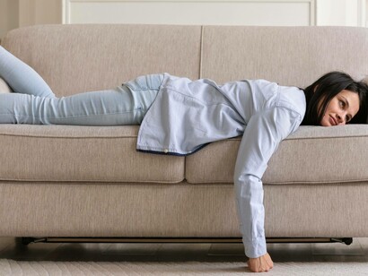 Donna sdraiata a pancia in giù su un divano: "Tutto crolla, come crolli tu sul divano"