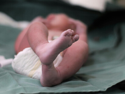 A newborn’s tiny feet rest gently on the hospital bed