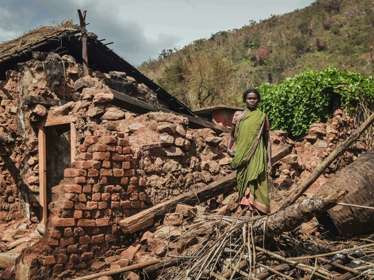 Woman standing near a house destroyed by an earthquake in India