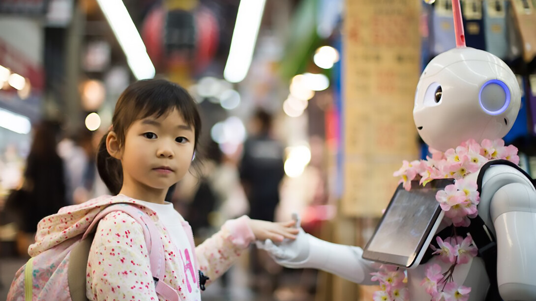 A photo of a girl resting her left hand on a white digital robot in Japan