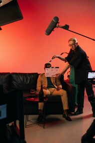 A director in a black shirt holds a clapperboard during filming