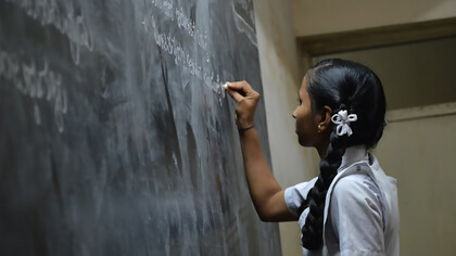 A student writing on the blackboard in a classroom, Bengaluru, India