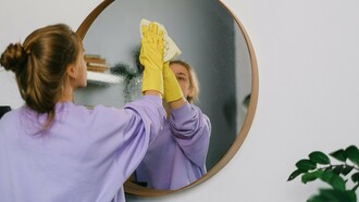 Une femme nettoyant un miroir soigneusement et se concentrant sur la tâche