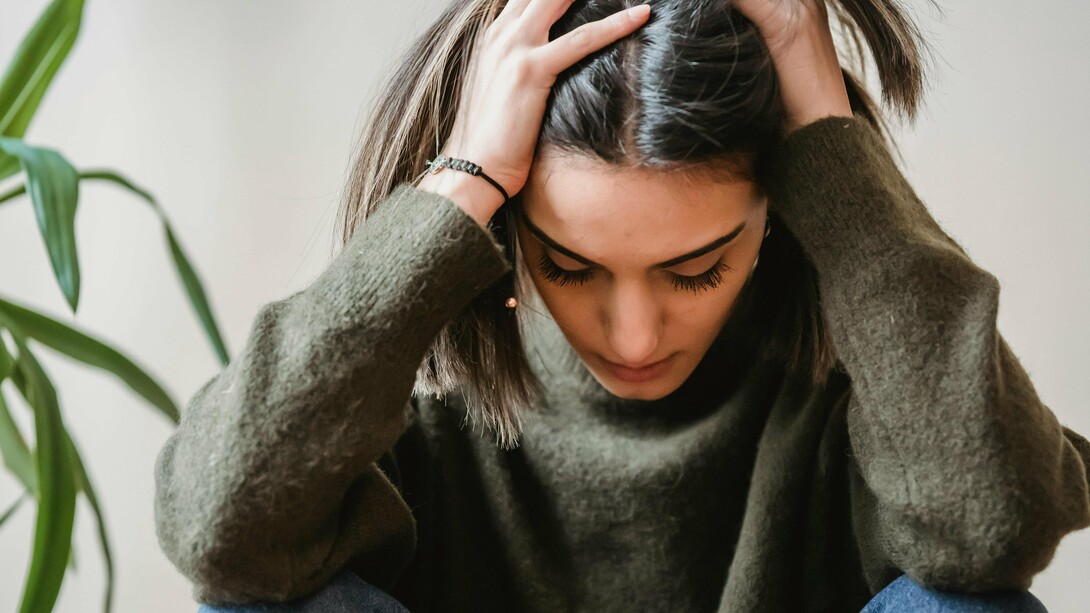 Une femme tenant sa tête dans la frustration, la douleur et la colère, probablement coincée dans une difficulté