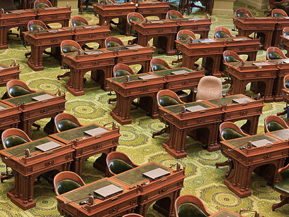 An empty California State Assembly chamber, chairs left vacant, USA