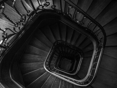 Grayscale photo of a spiral staircase with labyrinth-like architecture