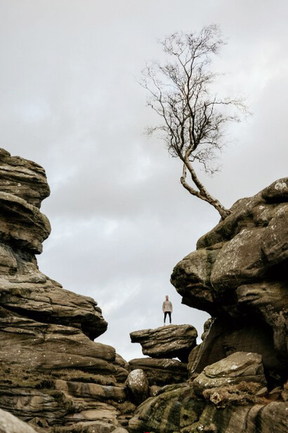 A person stands atop a rock formation under the bright daylight sky