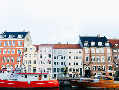 The vibrant boats contrast beautifully with the charming, historic buildings of Copenhagen, Denmark, creating a scenic waterfront view