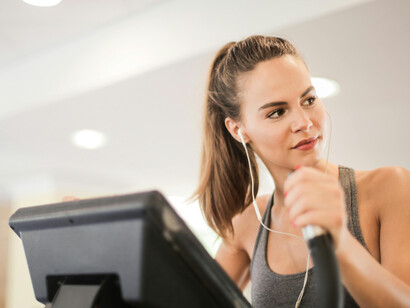 A young female athlete trains alone on a treadmill in a modern gym, focusing on HIIT, cardio, and overall fitness