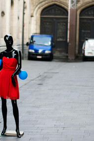 Black mannequin in a red dress displayed on the street