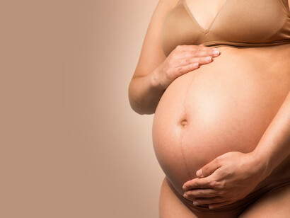 A pregnant woman cradles her belly with a gentle hand
