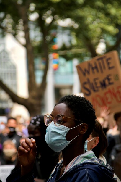 A man wearing a jacket and a mask, participating in an equality protest in Cologne, Germany