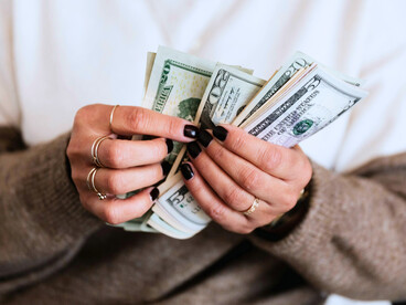 An individual counting cash in silence, representing the normalization of money as a primary concern