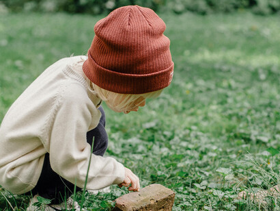 A little boy kneels in the backyard, using a plastic shovel to uncover a hidden treasure buried in the earth