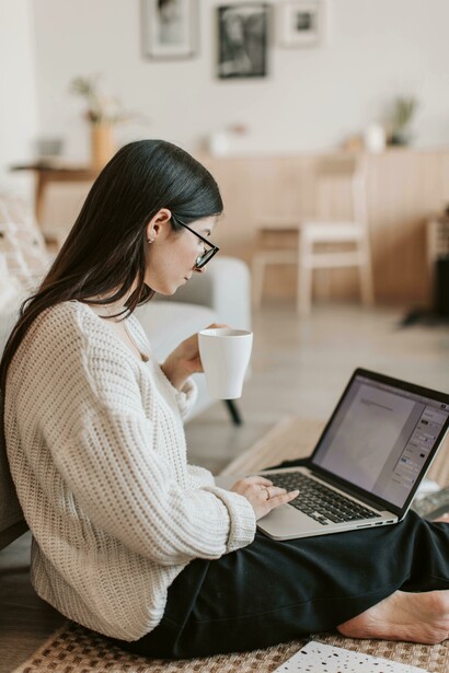 A content writer focused on her laptop, working from the living room floor