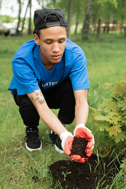 A man gently holding a young plant in his hands during a community reforestation effort as a volunteer